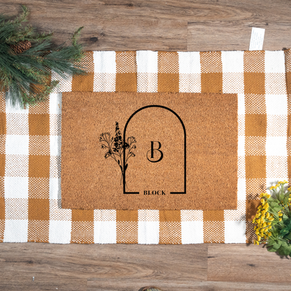 Doormat with decorative design and 'B' letter on a checkered fabric background