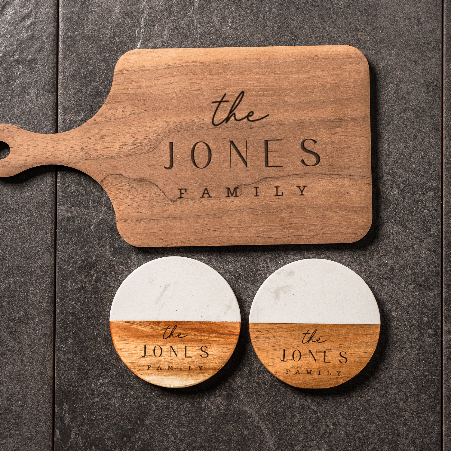 Wooden cutting board and coasters with 'the JONES FAMILY' engraving on a dark surface
