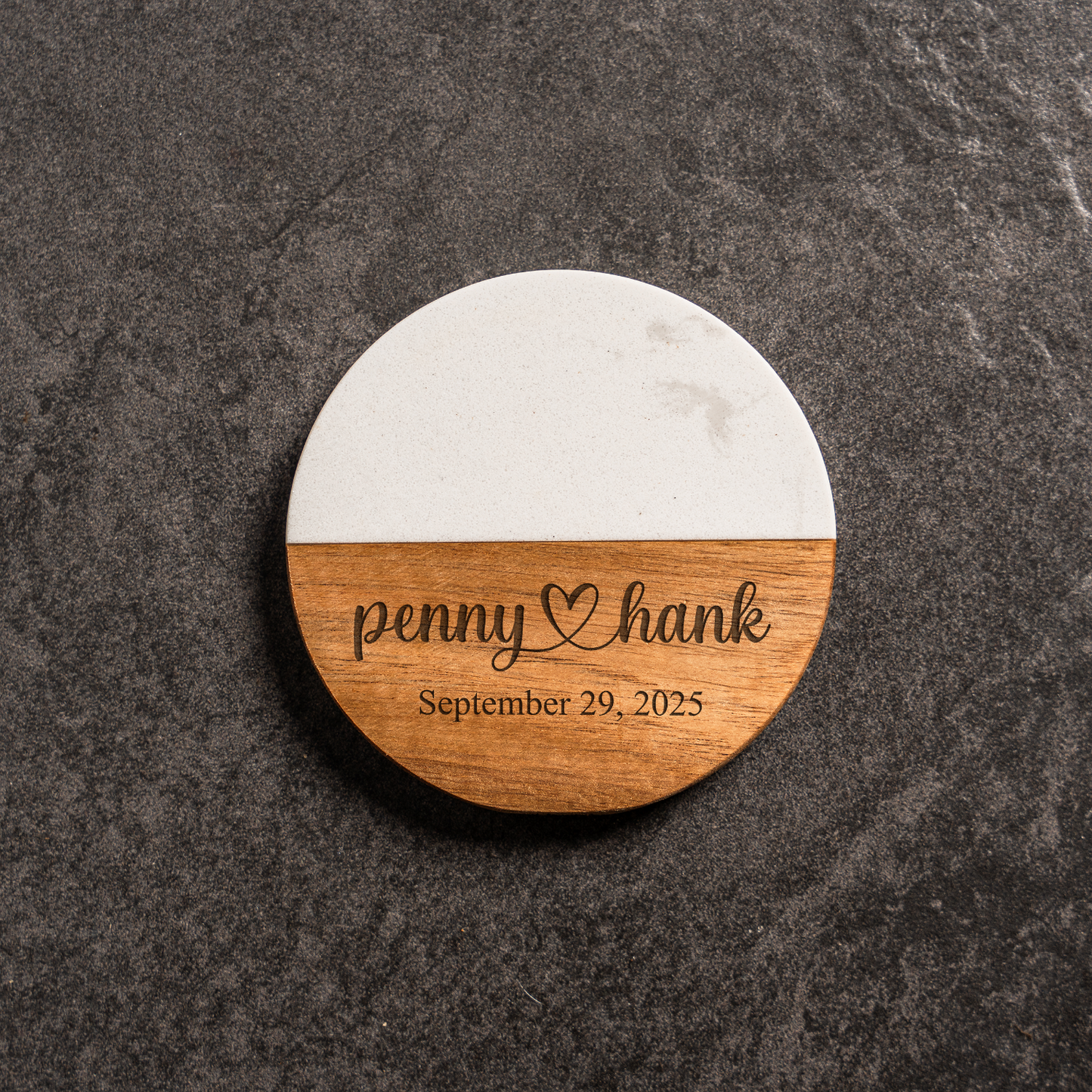 Round wooden coaster with marble bottom on a dark surface