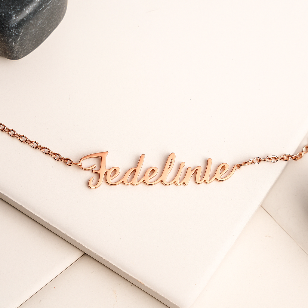 Rose gold necklace with 'Federlinie' engraving on a light wooden surface.